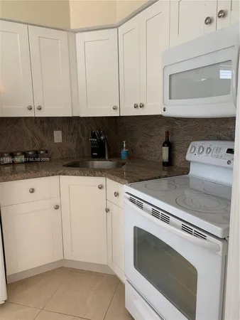 a kitchen with granite countertop white cabinets and white appliances