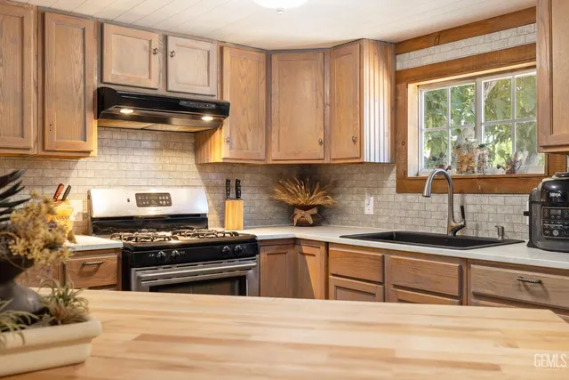 a room with furniture a large window and stainless steel appliances