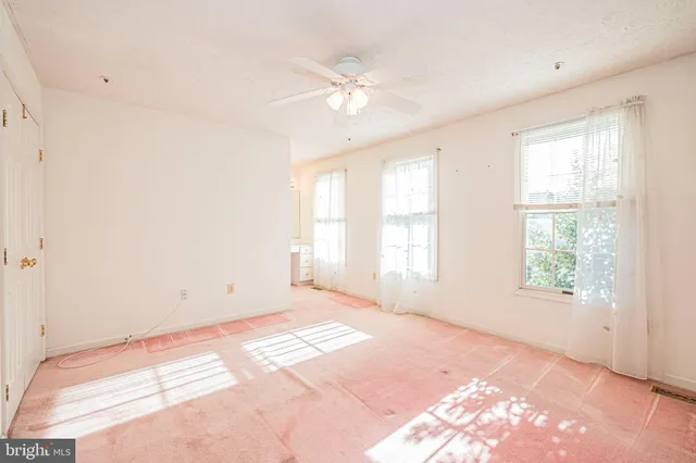 an empty room with windows and chandelier fan