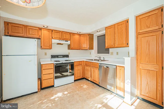 a kitchen with granite countertop a refrigerator stove top oven and sink