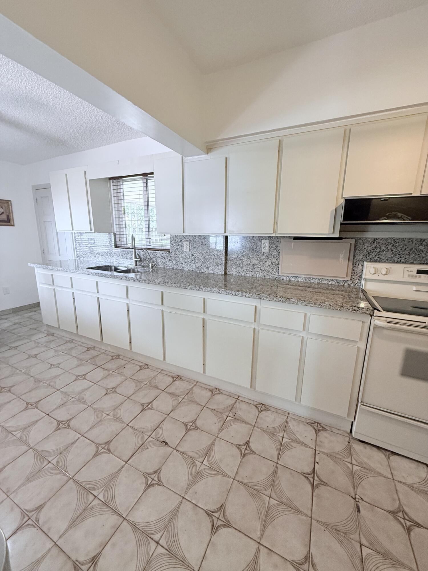 957 West 67th Street Hialeah, FL 33012 - Photo 6 of 15 a kitchen with granite countertop a sink white cabinets and white appliances