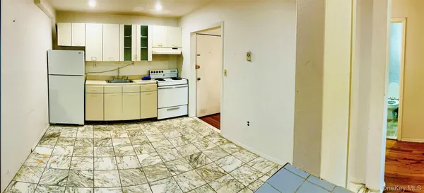 a kitchen with a refrigerator a stove top oven and a hallway