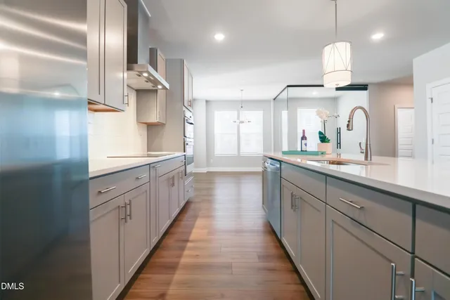 a large kitchen with a large counter top space a sink stainless steel appliances and cabinets