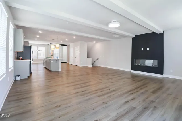 a view of an empty room and a kitchen