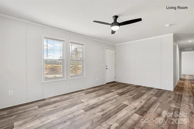 a view of empty room with wooden floor and ceiling fan