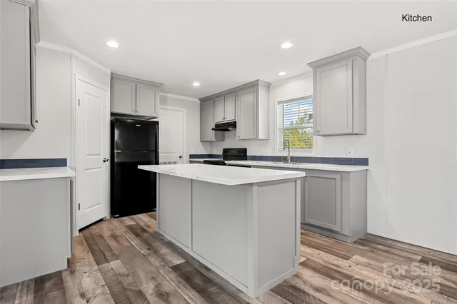 a kitchen with a refrigerator a stove top oven and white cabinets