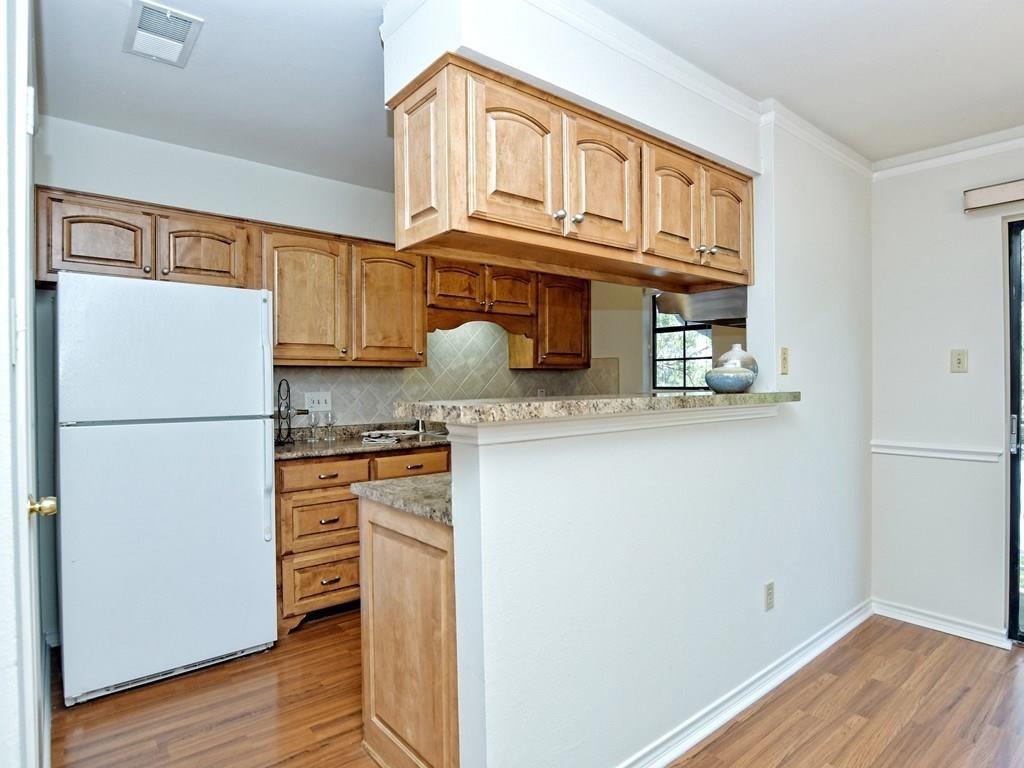 4159 Steck Avenue, Unit 278 Austin, TX 78759 - Photo 6 of 30 Kitchen with freestanding refrigerator, tasteful backsplash, light wood-type flooring, crown molding, and light stone counters