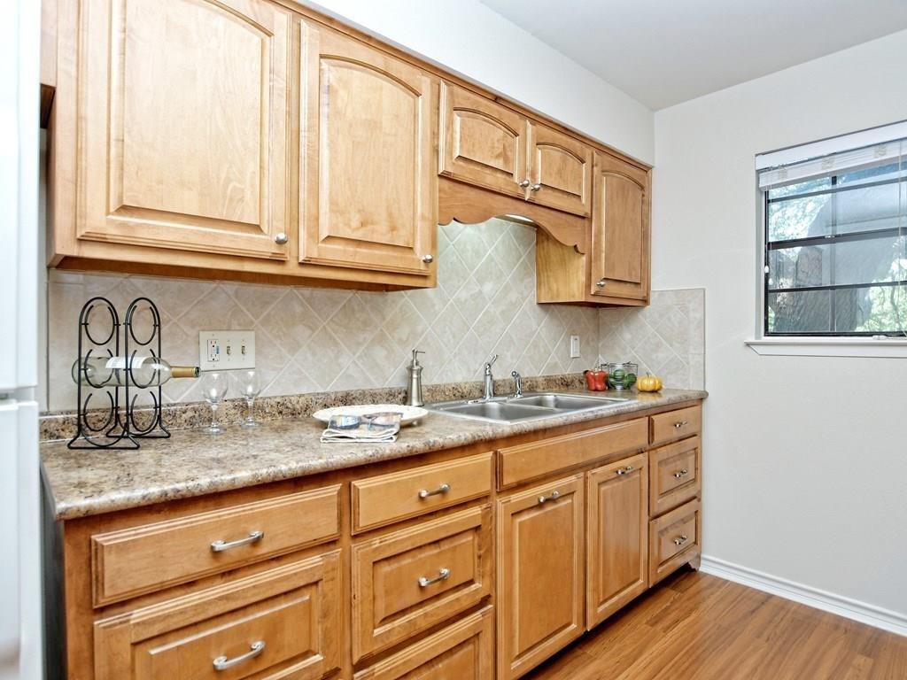 4159 Steck Avenue, Unit 278 Austin, TX 78759 - Photo 7 of 30 Kitchen with light wood-style flooring, freestanding refrigerator, light wood finish cabinetry, tasteful backsplash, and light stone counters