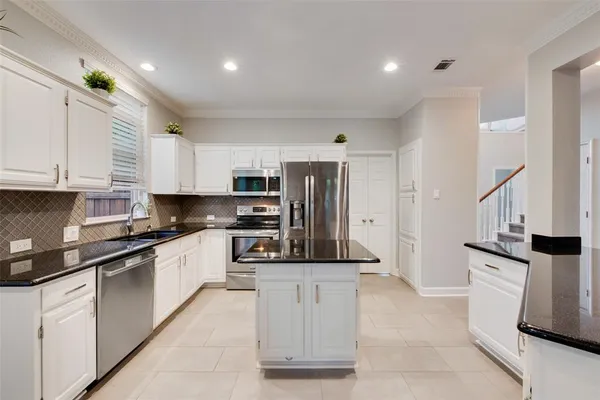 a kitchen with stainless steel appliances kitchen island granite countertop a refrigerator and a stove top oven