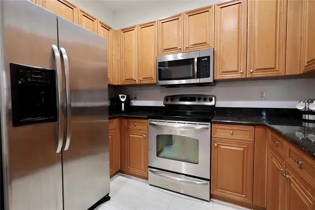 a kitchen with stainless steel appliances granite countertop white cabinets and a refrigerator