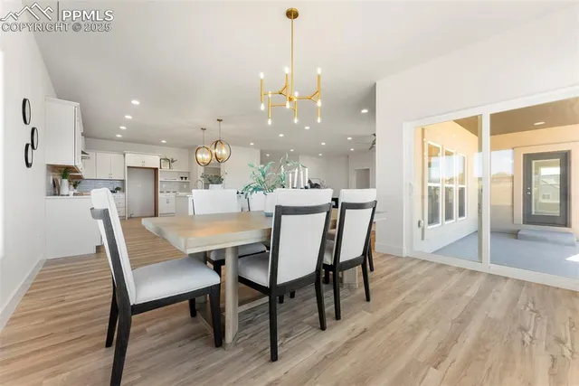 a dining room with wooden floor a chandelier a wooden table and chairs