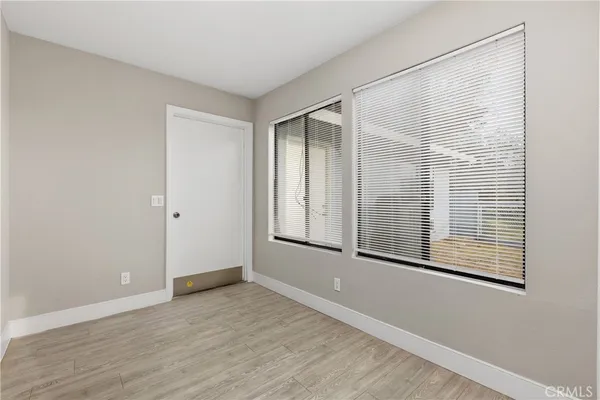 a view of an empty room with wooden floor and windows