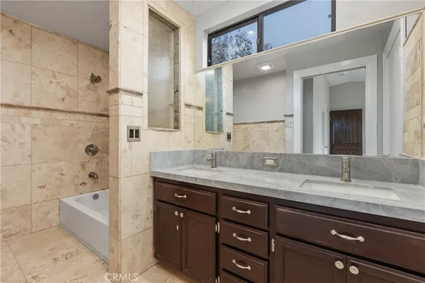 a bathroom with a granite countertop bathtub sink double and mirror