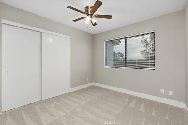 a view of an empty room with window and a ceiling fan