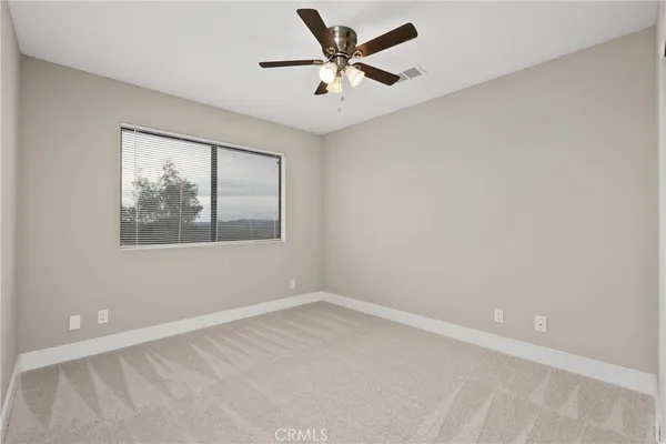 an empty room with a window and a ceiling fan