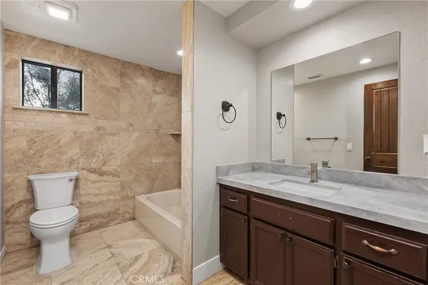 a bathroom with a granite countertop toilet a sink and a mirror