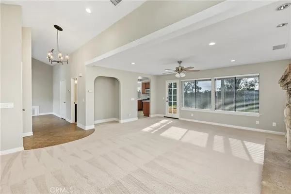 a view of an empty room with a window and chandelier