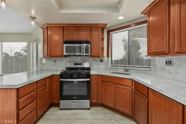 a kitchen with stainless steel appliances granite countertop wooden cabinets a stove top oven a sink and dishwasher