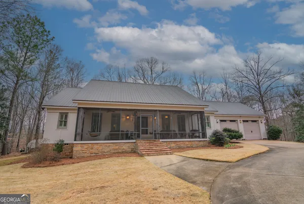 a view of a white house with a large tree and plants