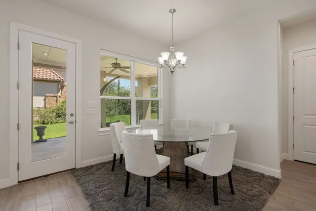 an empty room with chandelier fan and windows