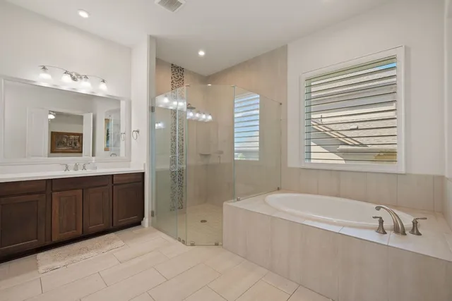 a bathroom with a tub a sink a mirror and a shower