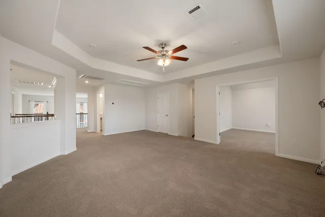 an empty room with chandelier fan and windows
