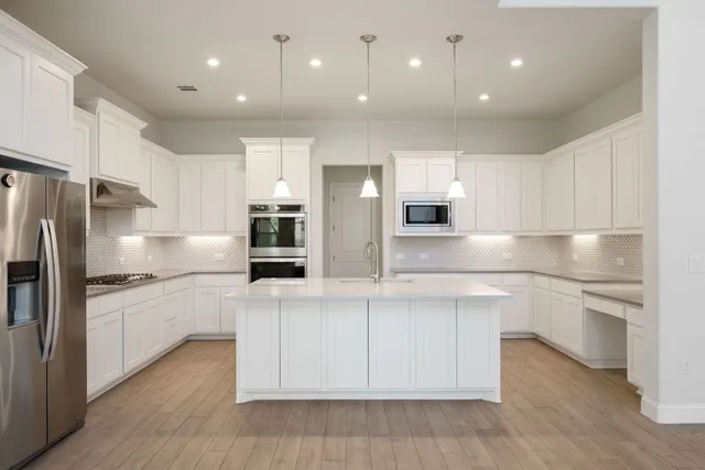 a kitchen with stainless steel appliances granite countertop a refrigerator and a stove top oven