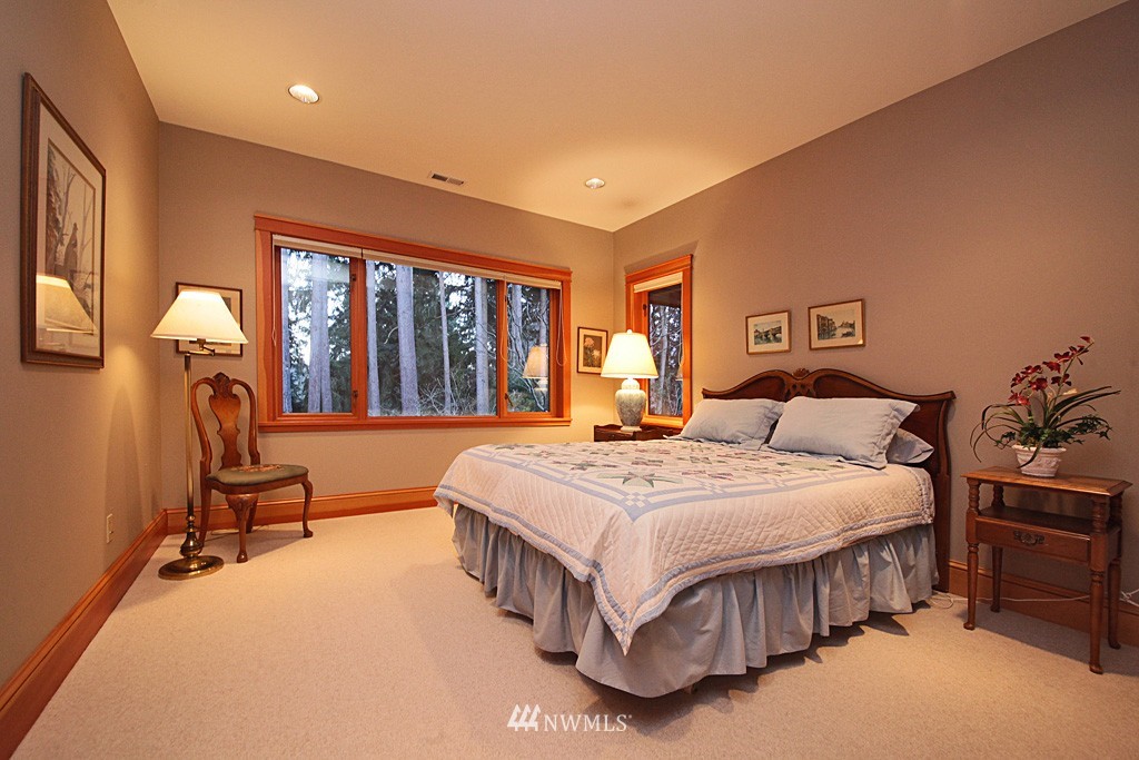 6966 Sills Road Clinton, WA 98236 - Photo 23 of 25 a spacious bedroom with a bed table and a large window
