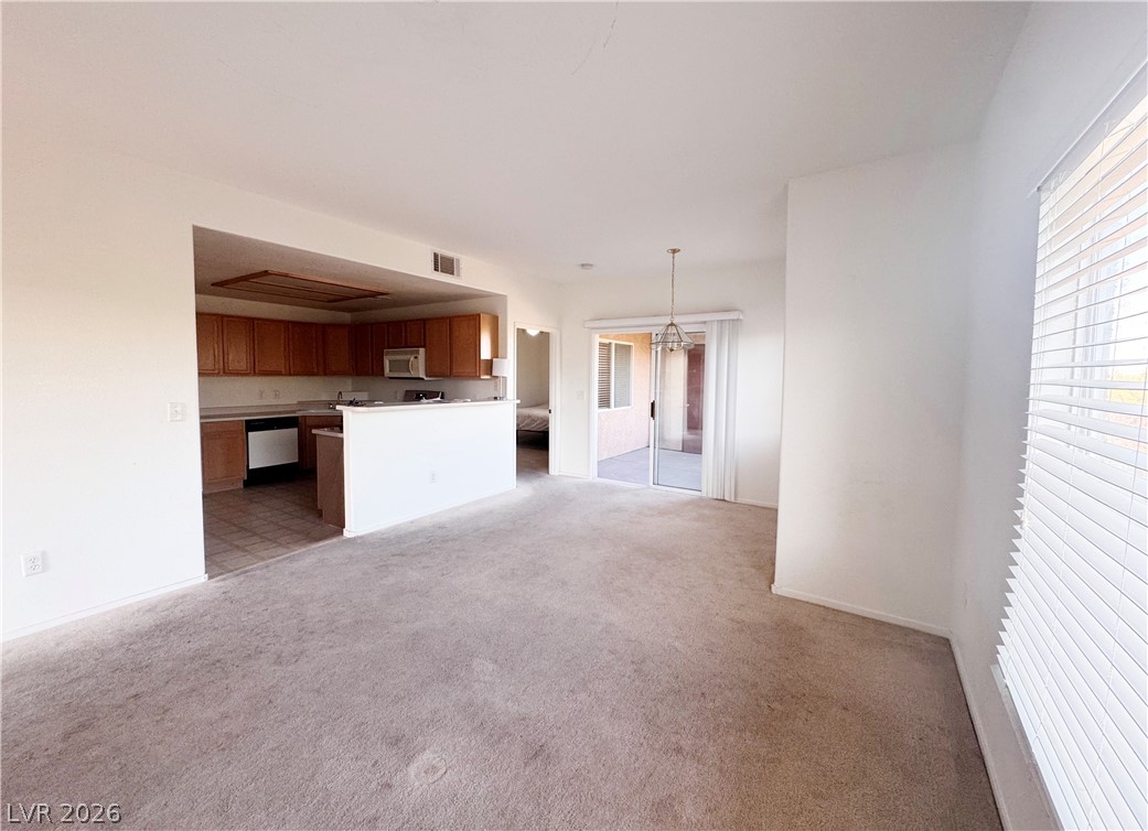 9580 West Reno Avenue, Unit 242 Las Vegas, NV 89148 - Photo 4 of 26 An inviting open-concept living area boasts direct patio access and a well-appointed kitchen.