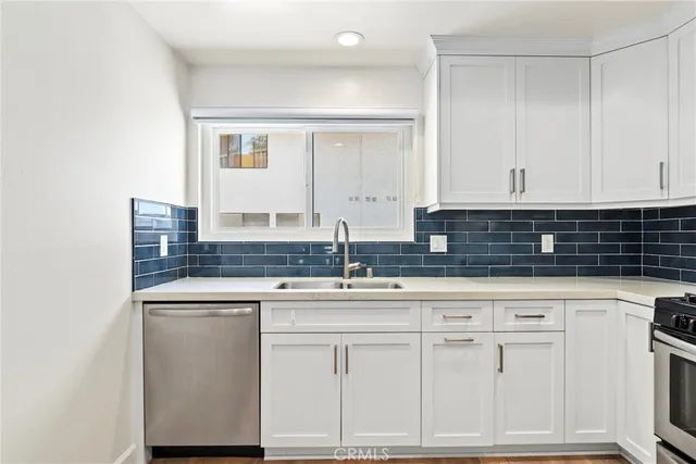 a kitchen with white cabinets and sink