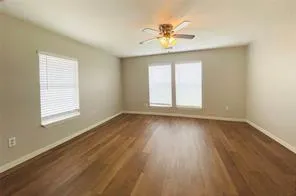 a view of an empty room with a window and wooden floor