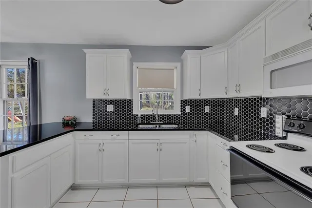 a kitchen with white cabinets a sink and white appliances