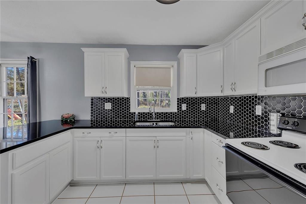 4385 Donegal Circle Lithia Springs, GA 30122 - Photo 13 of 32 a kitchen with white cabinets a sink and white appliances