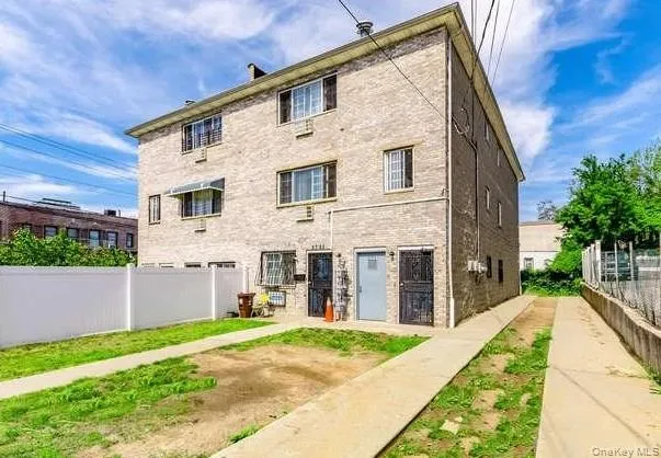 a view of a white house with a small yard and a large tree