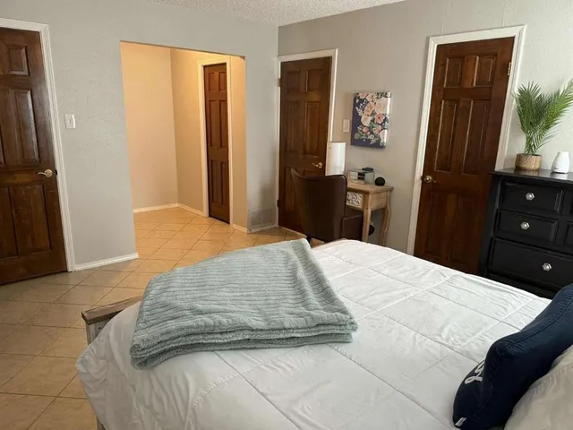 a bedroom with a bed and a large mirror next to a window