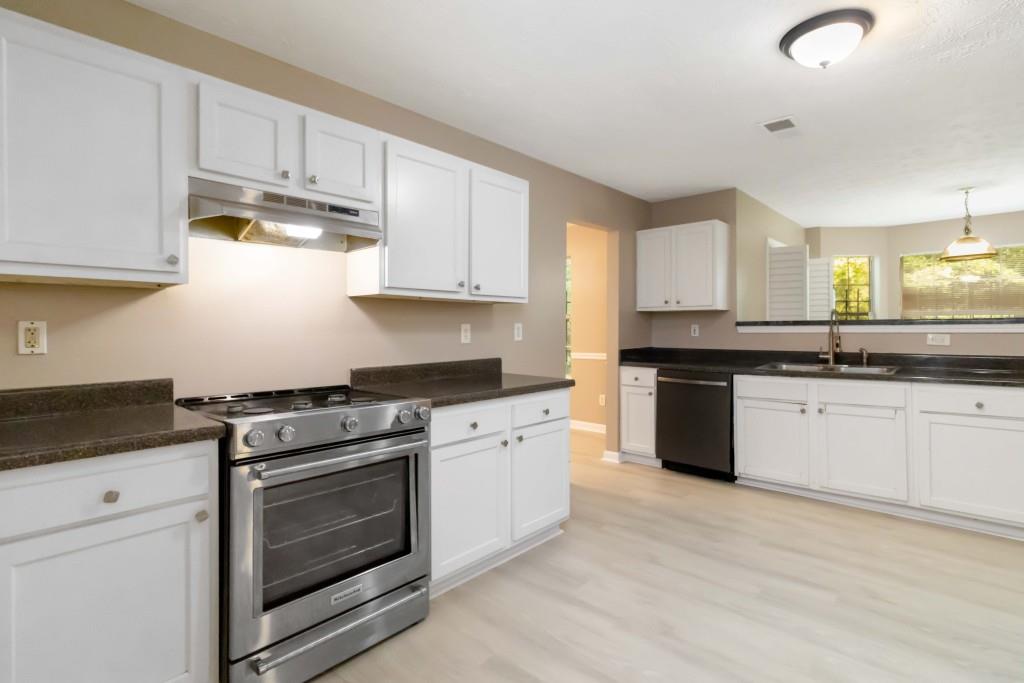 4783 Creekside Place Decatur, GA 30035 - Photo 6 of 24 a kitchen with granite countertop white cabinets and stainless steel appliances