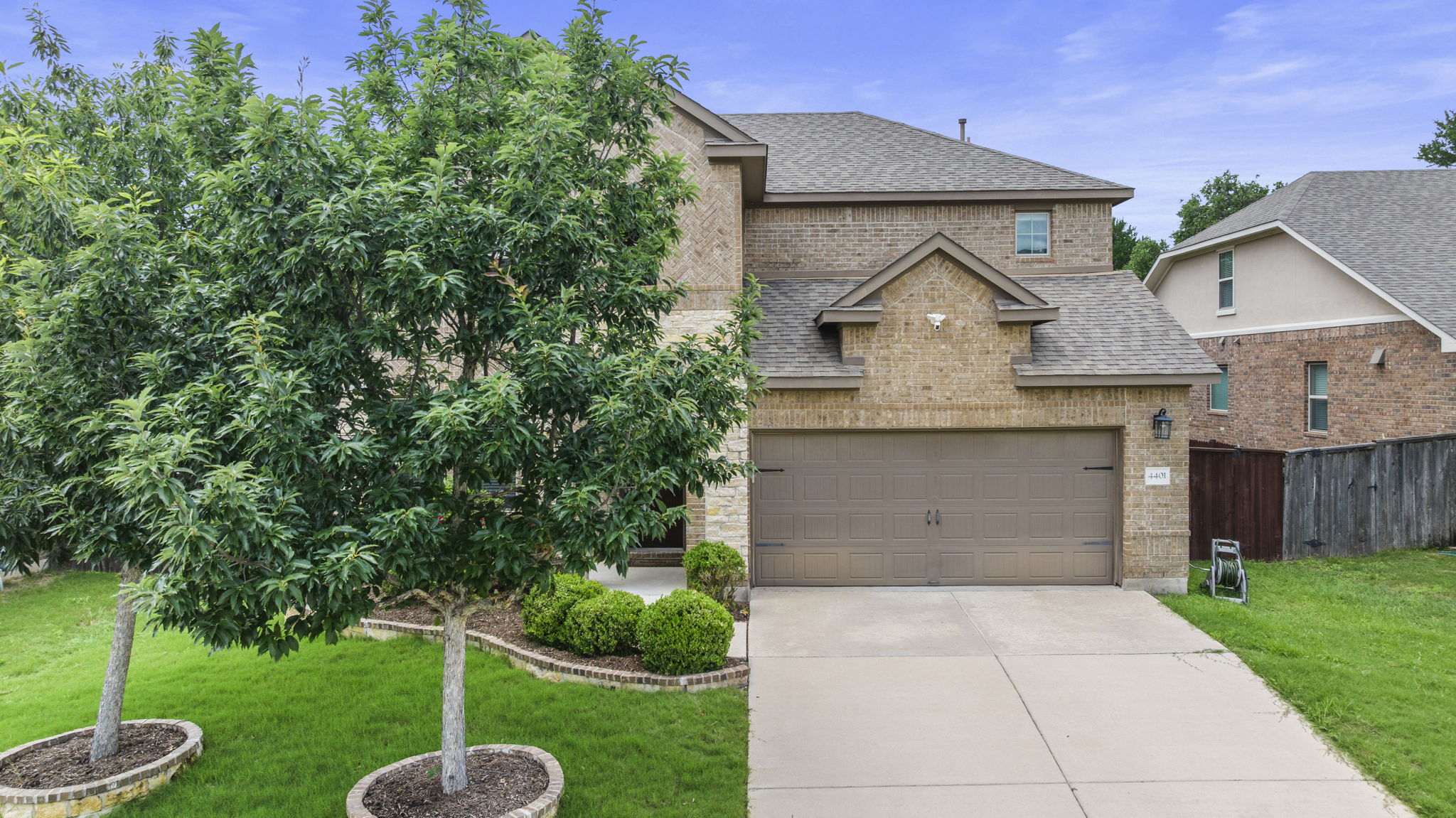 4401 Trinity Woods Street Leander, TX 78641 - Photo 2 of 37 A well-maintained facade features brick and stone accents, complemented by mature trees and manicured landscaping.