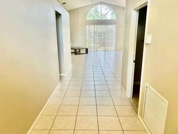 a view of kitchen and empty room with wooden floor
