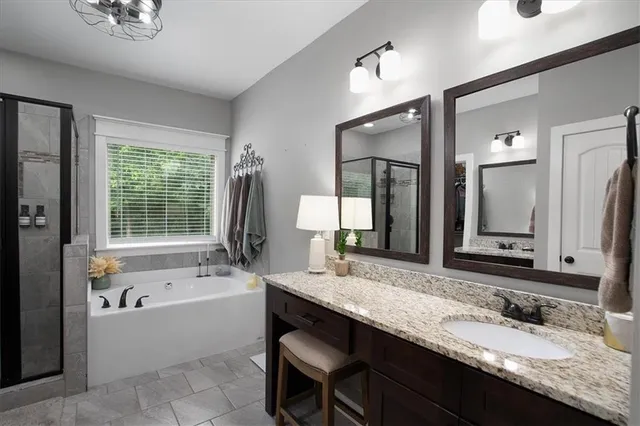 a bathroom with a granite countertop tub a double vanity sink and a large mirror