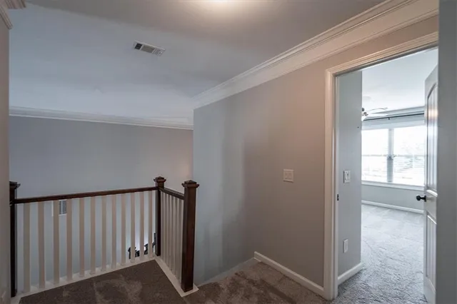a view of a hallway with wooden floor and a bathroom