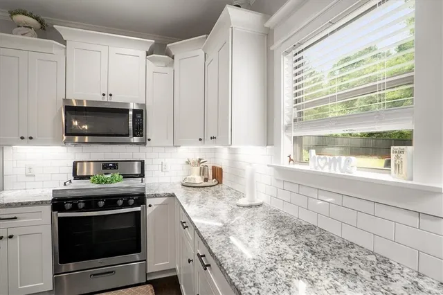 a kitchen with granite countertop a stove a sink and a microwave