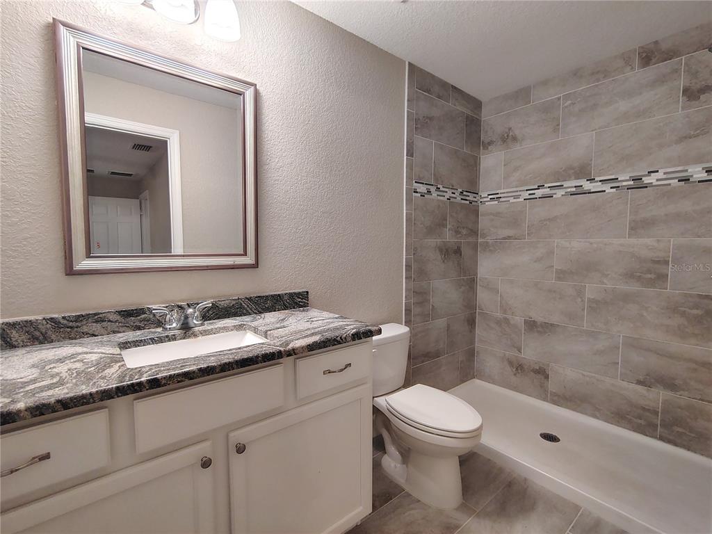 13093 Southwest 35th Circle Ocala, FL 34473 - Photo 6 of 15 a bathroom with a granite countertop sink a toilet and shower