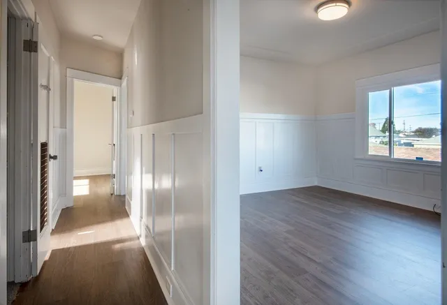 a view of a hallway with wooden floor and a living room