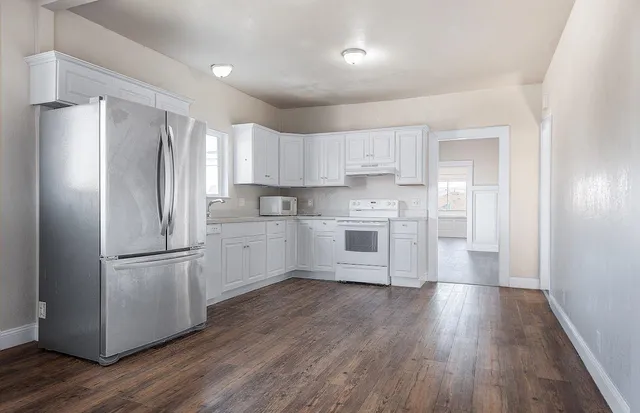 a kitchen with a refrigerator a sink and wooden floor