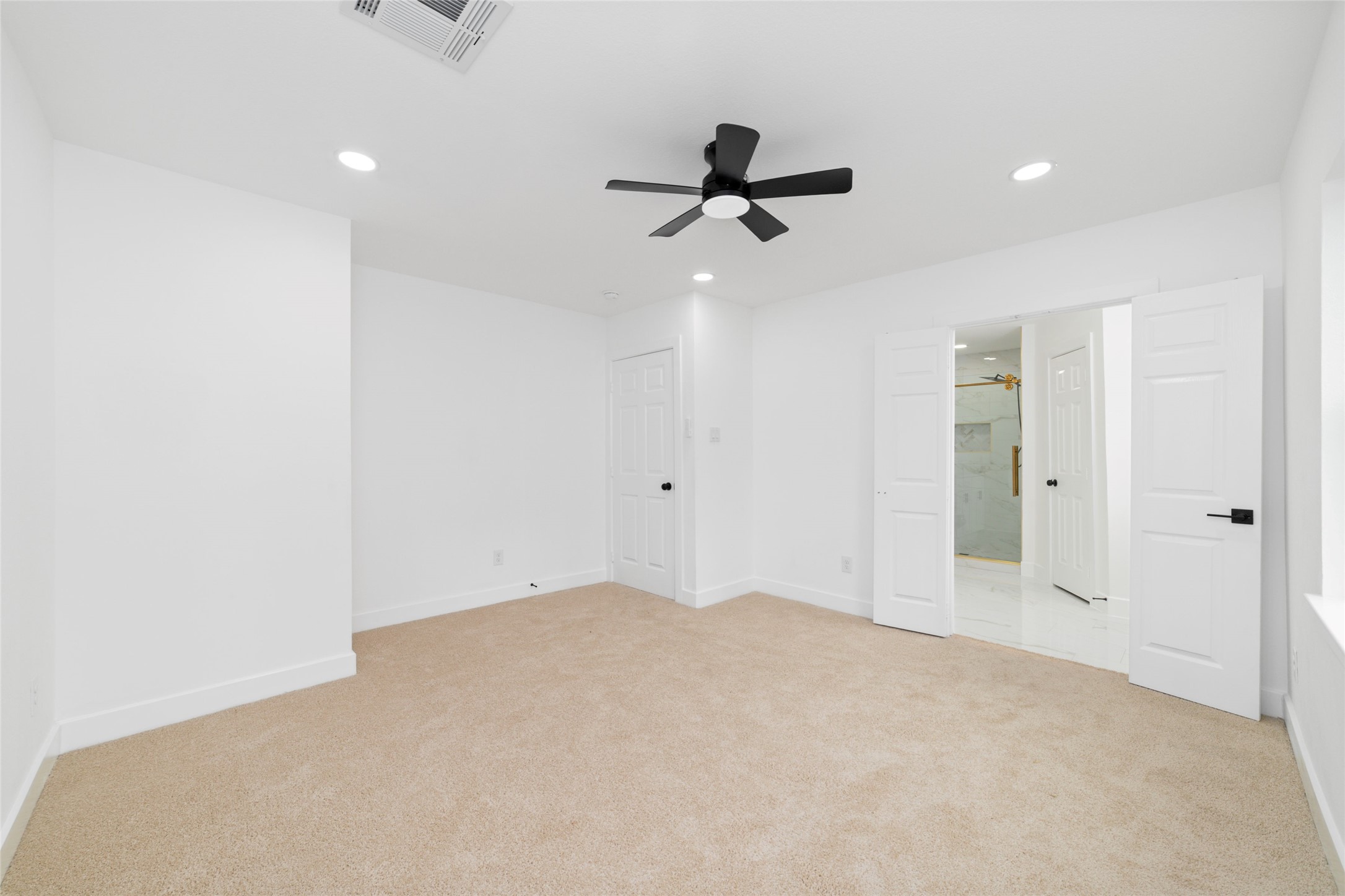 5709 Langley Road Houston, TX 77016 - Photo 15 of 27 The Master Bedroom features plush carpet, recessed lighting, and a modern ceiling fan. It includes a doorway leading to a bathroom, enhancing convenience and privacy.