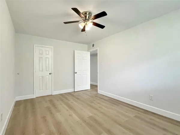 an empty room with ceiling fan and window