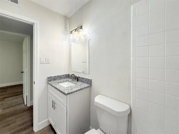 a bathroom with a granite countertop sink a toilet and a mirror