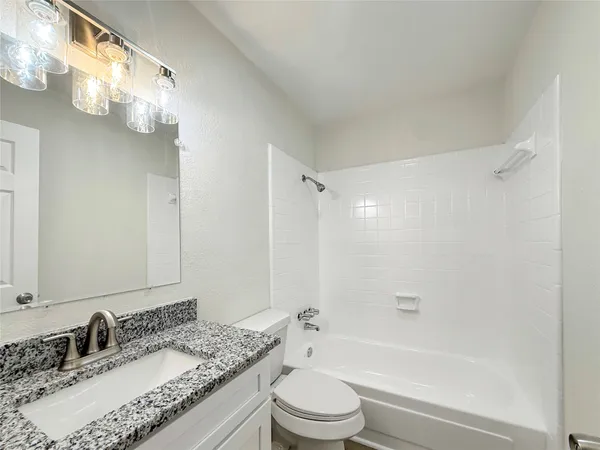a bathroom with a granite countertop sink a toilet and shower
