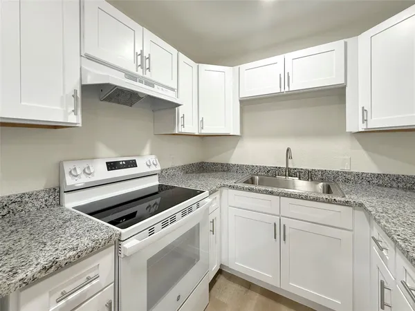 a kitchen with granite countertop white cabinets and white appliances