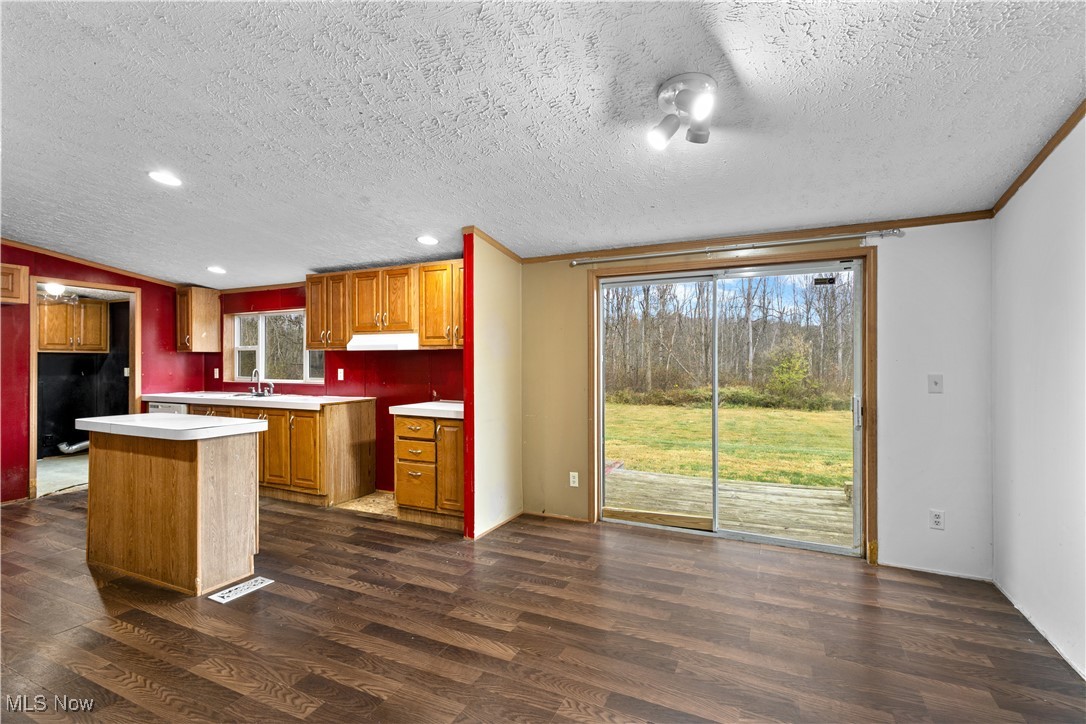 12859 Narrows Road Cambridge, OH 43725 - Photo 13 of 29 Kitchen with a textured ceiling, a center island, ornamental molding, and dark wood-type flooring